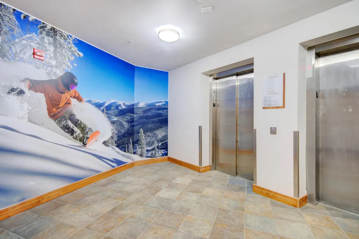 A corridor with elevators and a dynamic snowboarding mural, suggesting easy access to all levels of the resort and celebrating the adventurous spirit of the location.
