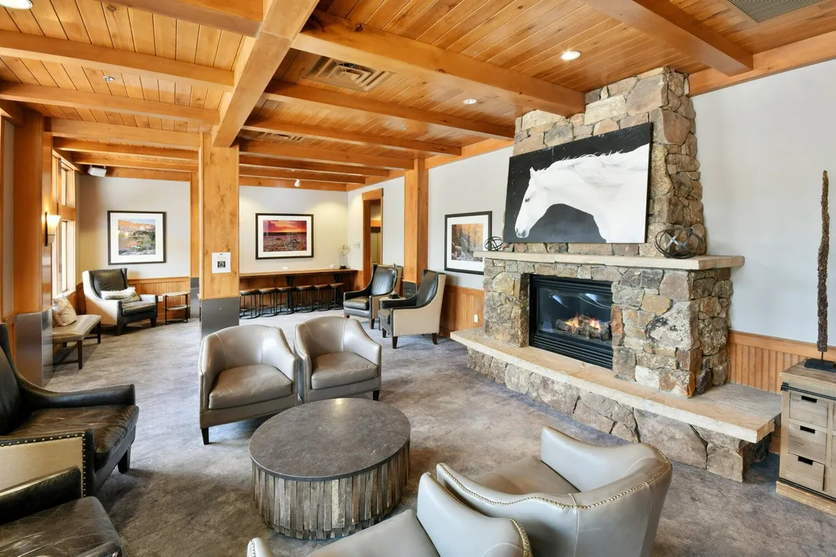 A cozy living room featuring a glowing gas fireplace, comfortable seating arranged for conversation, and artwork on the walls. The space is warm and inviting, perfect for relaxing after a day on the slopes or gathering for movie nights.